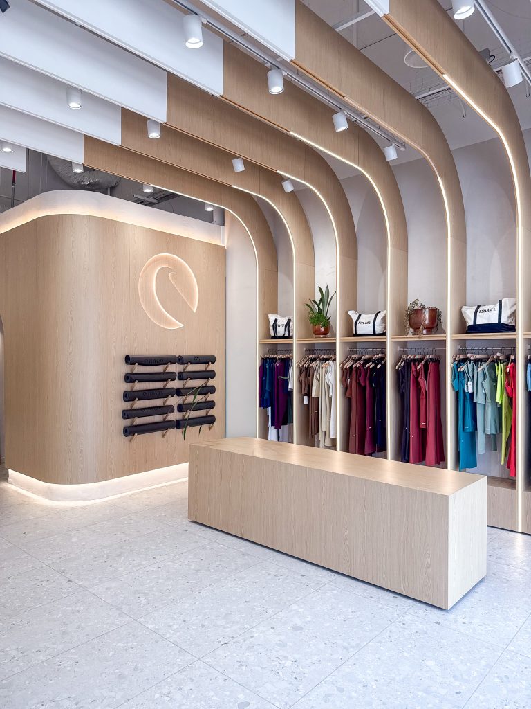 עיצוב חנות בגדי ספורט לנשים בחיפה עם קשתות מוארות, קירות תצוגה ונגרות בהתאמה אישית