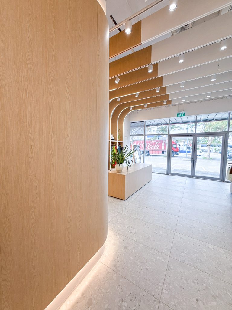 עיצוב חנות בגדי ספורט לנשים בחיפה עם קירות עץ מעוגלים ותאורה נסתרת